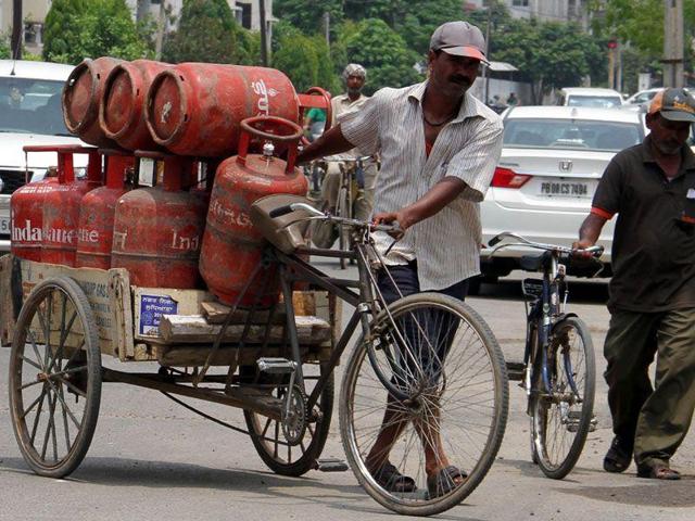 A delivery man carries LPG cylinders at Kitchlu Nagar in Ludhiana.(HT File Photo)