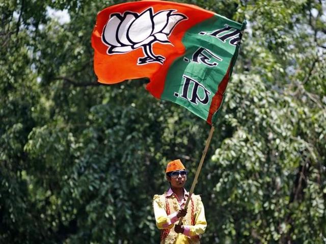 A supporter of Bharatiya Janata Party (BJP) waves the party flag results outside the party headquarters in New Delhi.(Reuters Photo)