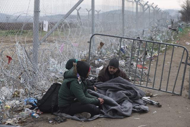 Refugees wait at the border crossing next to a wire fence that separates the Greek side from the Macedonian one at the northern Greek border station of Idomeni, Sunday, Feb. 28, 2016. (AP)