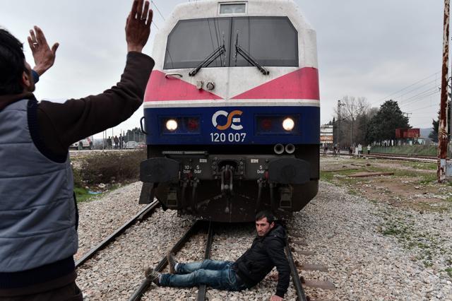 Syrian and Iraqi refugees trapped at the Greek-Macedonian borders stop an arriving train during their protest. (AFP)