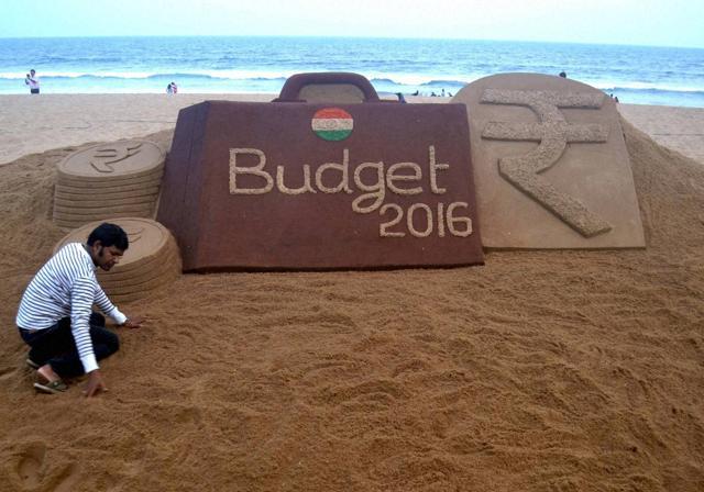 Sand artist Sudarsan Pattnaik makes a sand sculpture on the upcoming Budget 2016 at Puri Sea beach of Odisha. (PTI Photo)