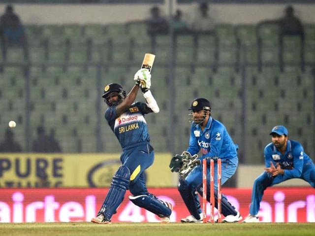 Sri Lanka's Chamara Kapugedera (L) plays a shot as Mahendra Singh Dhoni (C) looks on. (AFP Photo) 