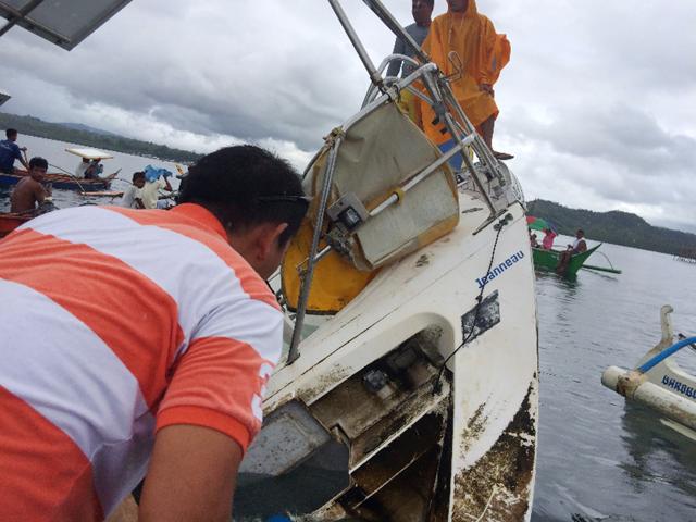 This recent undated handout photo released by Barobo police station on March 2, 2016 shows people standing on a partially-capsized boat believed to be owned by German national Manfred Fritz Bajorat whose body was found inside, after residents found the yatch drifting off the coast of Barobo. (AFP)