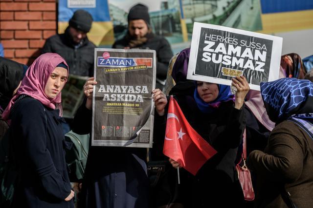 A Zaman supporter holds the latest edition of Turkish daily newspaper Zaman with the headline 'Suspended the constitution' while another holds a placard reading "Zaman won’t be silent" in front of the newspaper's headquarters in Istanbul. (AFP Photo) A Zaman supporter holds the latest edition of Turkish daily newspaper Zaman with the headline 'Suspended the constitution' while another holds a placard reading "Zaman won’t be silent" in front of the newspaper's headquarters in Istanbul. (AFP Photo)
