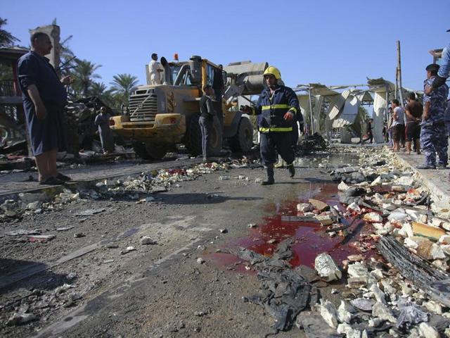 Civilians and security forces gather as a municipality bulldozer cleans up the scene of a suicide bomb attack in Hillah, about 95 kilometres south of Baghdad, Iraq. (AP Photo) Civilians and security forces gather as a municipality bulldozer cleans up the scene of a suicide bomb attack in Hillah, about 95 kilometres south of Baghdad, Iraq. (AP Photo)