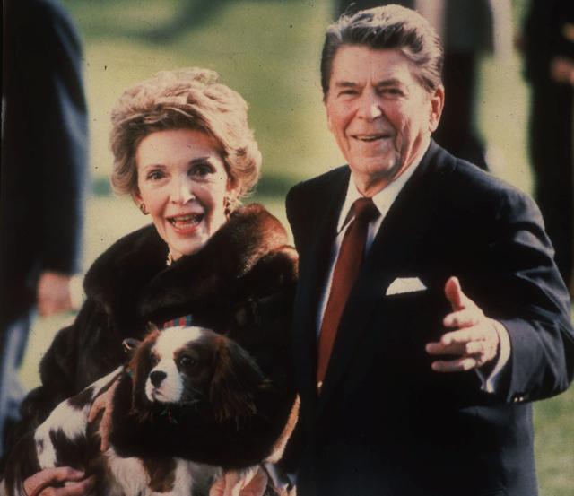First Lady Nancy Reagan holding the Reagans' pet Rex, a King Charles spaniel, as she and President Reagan walk on the White House South lawn. (AP Photo)