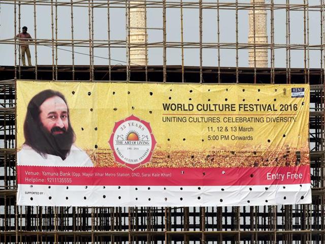 A labourer stands over a World Culture Festival banner on a structure being constructed for the event on the banks of the Yamuna in New Delhi.(AFP photo)