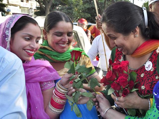 AAP activists giving flowers to the commuters at Bhai Bala chowk in Ludhiana on Tuesday. (Sikander Singh Chopra/HT)