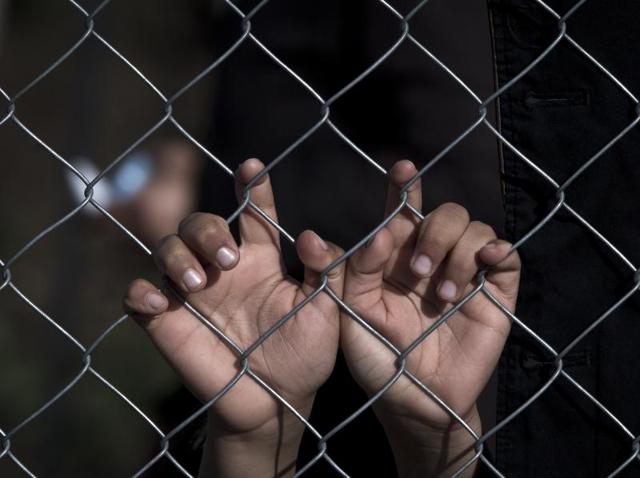 A migrant boy peers between pants hanging on a fence at the northern Greek border station of Idomeni, Tuesday, March 8, 2016. (AP Photo) A migrant boy peers between pants hanging on a fence at the northern Greek border station of Idomeni, Tuesday, March 8, 2016. (AP Photo)