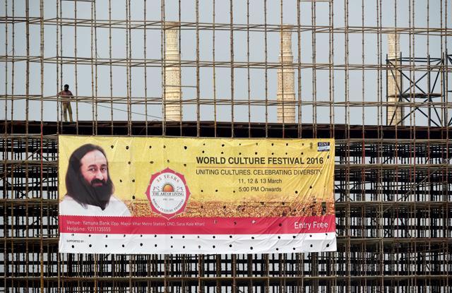 A labourer stands over a World Culture Festival banner on a structure being constructed for the event on the banks of the Yamuna in New Delhi (AFP Photo) A labourer stands over a World Culture Festival banner on a structure being constructed for the event on the banks of the Yamuna in New Delhi (AFP Photo)