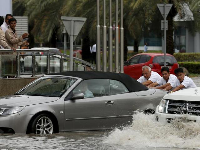People push a car through flood waters during a rain storm in Dubai. (REUTERS) People push a car through flood waters during a rain storm in Dubai. (REUTERS)