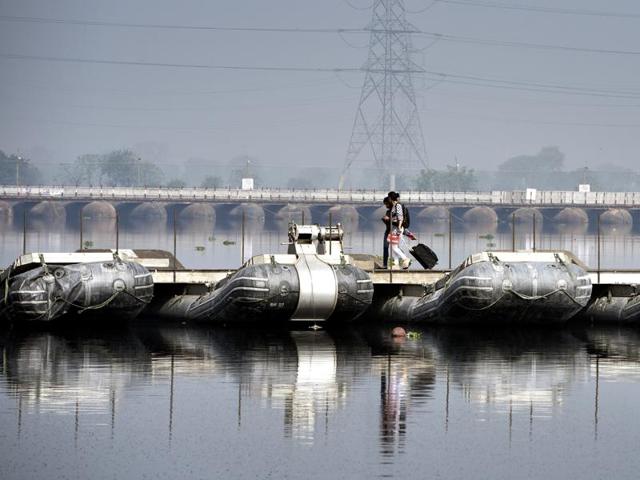 Two women walk on a pontoon bridge on the ecologically-sensitive Yamuna floodplains. (Sushil Kumar/ht photo) 