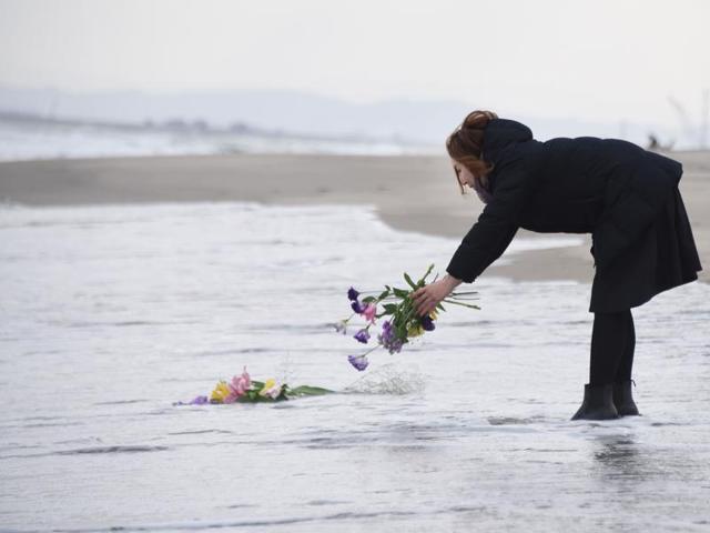A woman puts flowers into the sea to pray for victims of the 2011 earthquake and tsunami in Sendai, northern Japan. (AFP Photo)