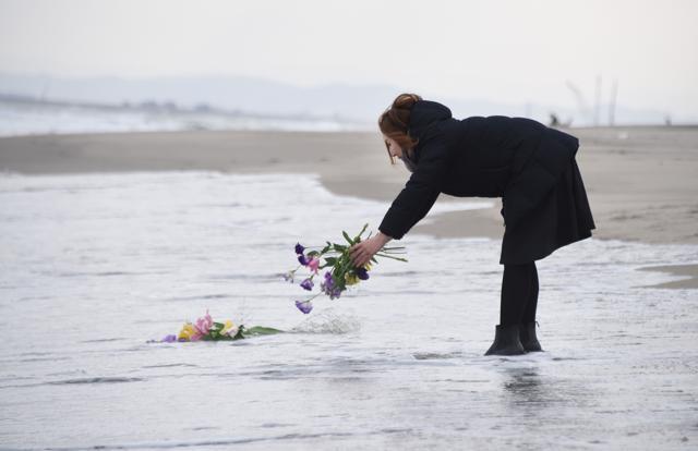 A woman puts flowers into the sea to pray for victims of the 2011 earthquake and tsunami in Sendai. (AFP Photo)