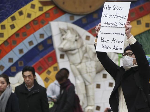 A man displays a sign remembering the March 11, 2011 earthquake and tsunami in Shibuya, Tokyo. (AP Photo)