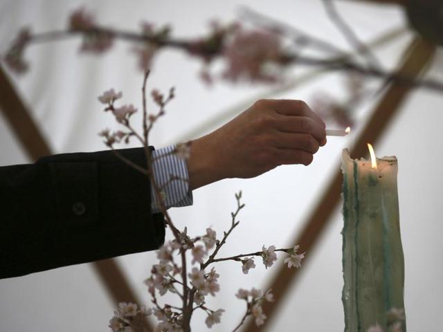 A man lights a candle to mourn for victims of the 2011 earthquake and tsunami before a memorial event in Tokyo. (AP Photo)