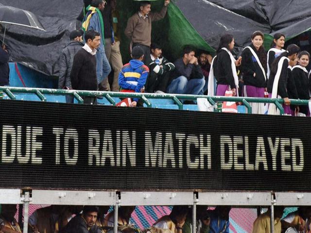 Spectators try to protect themselves under a structure and plastic sheets the T20 World Cup match between Oman and Netherlands was delayed. (PTI Photo)