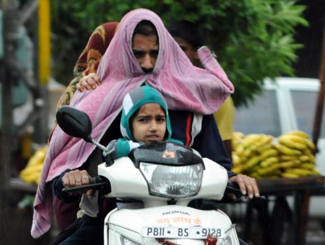 A family amid heavy rain in Patiala on Saturday. (bharat bhushan/ht)