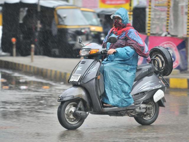 A woman rides through rain in Jalandhar. (Pardeep Pandit/ht)