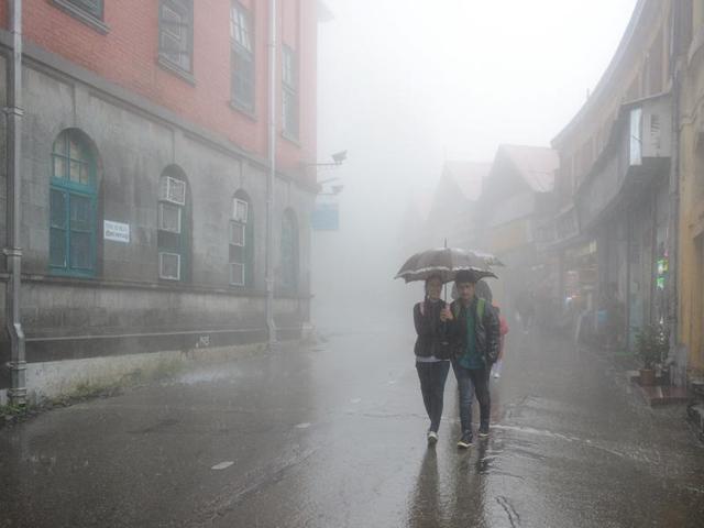 Students walk through rain and fog at Mall Road, Shimla, on Saturday. (Deepak sansta/HT)