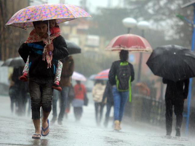 A boy carries his sister during heavy rain at the Ridge in Shimla on Saturday. (deepak sansta/HT)