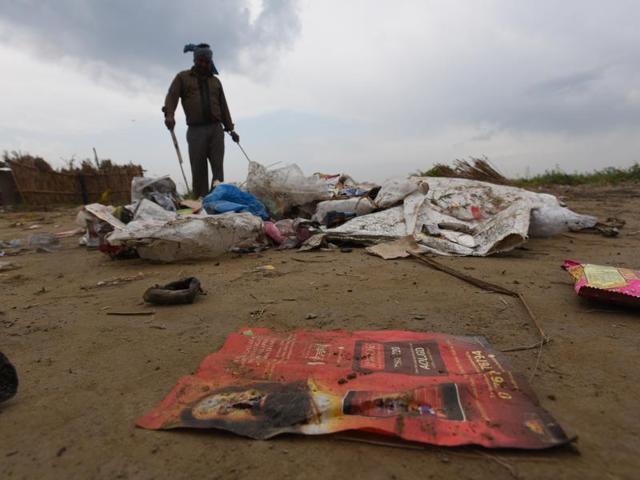 A farmer removes garbage after the World Culture Festival ended on Sunday. (Raj K Raj/ HT photo) 