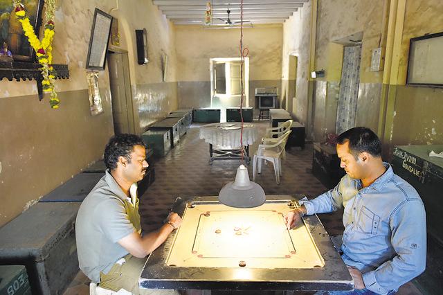 Bartolomue Mascarenhas, 39, chief cook on a tanker, and Agnew Fernandes, 32, a waiter on a cruise ship, play carom on a Sunday afternoon at the Club of Paroda in Matharpacady, Mazgaon. They would have played cricket, they say, if there were more members around. (Arijit Sen/ HT Photo)