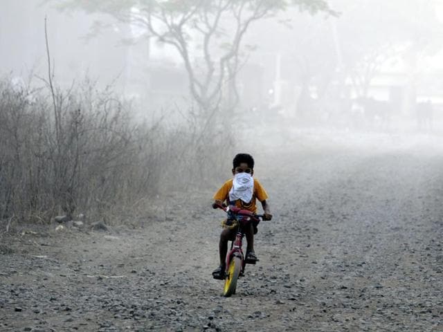 A child cycles near the trenching ground with his face covered to protect him from the smoke.(Shankar Mourya/ HT file)