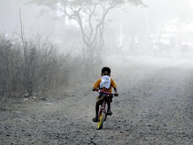 A child cycles near the trenching ground with his face covered to protect him from the smoke. (Shankar Mourya/ HT file) A child cycles near the trenching ground with his face covered to protect him from the smoke. (Shankar Mourya/ HT file)