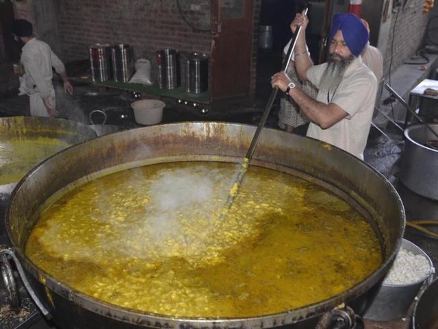 SGPC employee preparing organic ‘dal’ at langar hall of Golden Temple in Amritsar on Monday.(Sameer Sehgal/HT Photo)