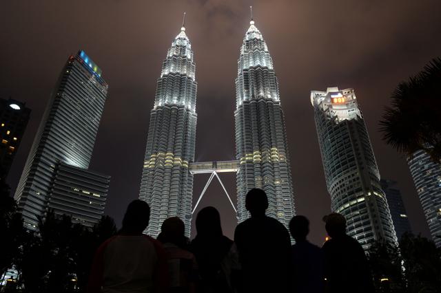 People stand in front of Malaysia's landmark Petronas Twin Towers before the lights went off in Kuala Lumpur. (AFP Photo) People stand in front of Malaysia's landmark Petronas Twin Towers before the lights went off in Kuala Lumpur. (AFP Photo)