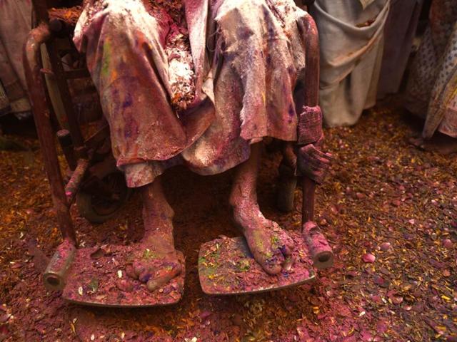 An old woman sits on her chair amid Holi celebrations.It is for the first time Holi celebration was organised at an ancient Gopinath Temple of Lord Krishna in which around a thousand widows from Vrindavan and Varanasi splashed colour at each other. (Ajay Aggarwal/HT Photo)