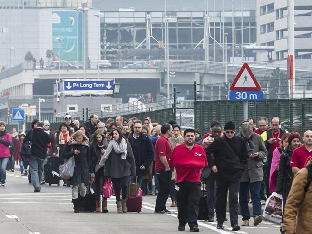 People walk away from the broken windows at Zaventem Airport in Brussels after an explosion on Tuesday. (AP) People walk away from the broken windows at Zaventem Airport in Brussels after an explosion on Tuesday. (AP)