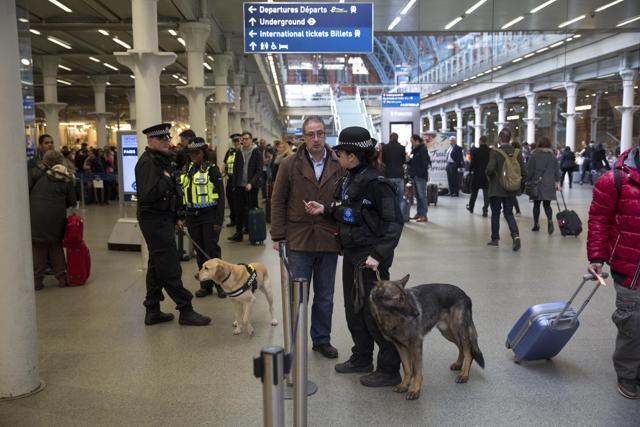 Police dog handlers speak to travellers as they patrol at St Pancras international railway station in London after Eurostar train services were suspended on the Brussels route after the attacks in Belgium on Tuesday. (AP)