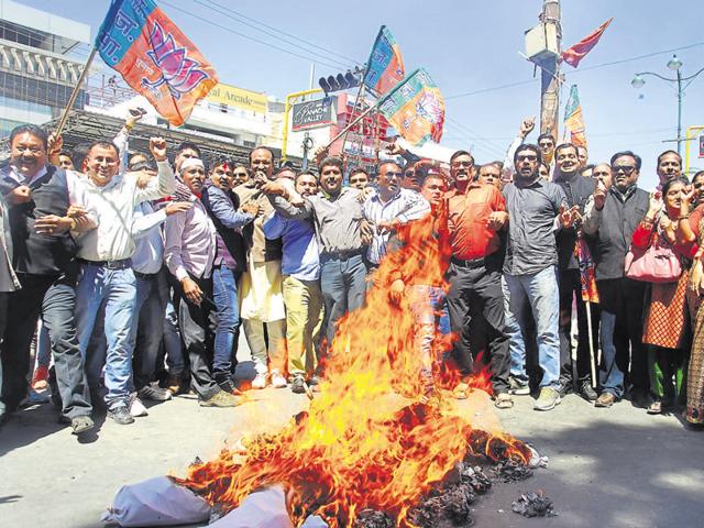 BJP workers burn effigies of chief minister Harish Rawat and speaker Govind Singh Kunjwal in Dehradun on Tuesday.(Vinay Santosh Kumar/HT Photo)