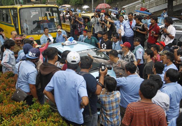 A taxi is stopped for not taking part in a protest by taxi drivers in Jakarta. (REUTERS) A taxi is stopped for not taking part in a protest by taxi drivers in Jakarta. (REUTERS)