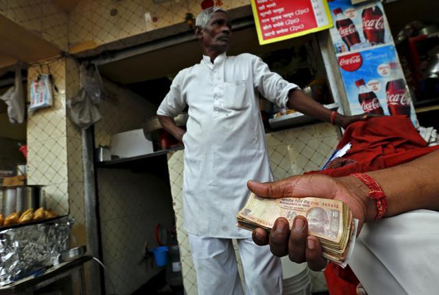 A street side restaurant owner holds a bundle of rupee notes as he stands outside his restaurant in New Delhi. (Reuters) A street side restaurant owner holds a bundle of rupee notes as he stands outside his restaurant in New Delhi. (Reuters)