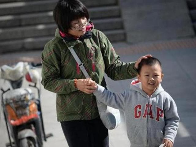A woman takes a child's hand as they walk through an underpass in Beijing. (AFP Photo) A woman takes a child's hand as they walk through an underpass in Beijing. (AFP Photo)
