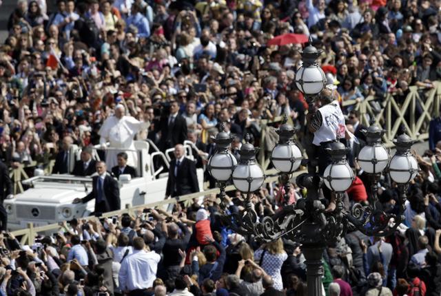 A man climbs on a street lamp as Pope Francis leaves at the end of the Easter mass in St. Peter's Square at the Vatican on Sunday (AP) A man climbs on a street lamp as Pope Francis leaves at the end of the Easter mass in St. Peter's Square at the Vatican on Sunday (AP)
