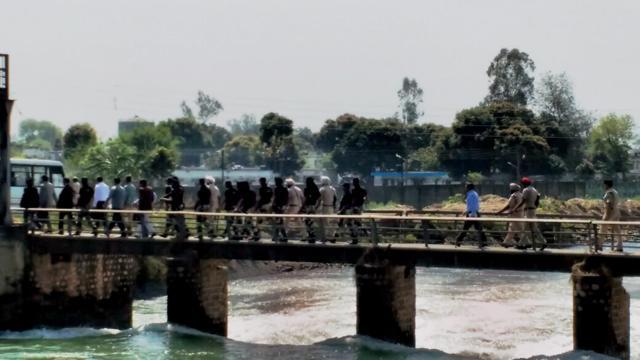 The Pakistani team cross a bridge over Oonj river in Bamiyal sector near the Pathankot base on Tuesday. (PTI)