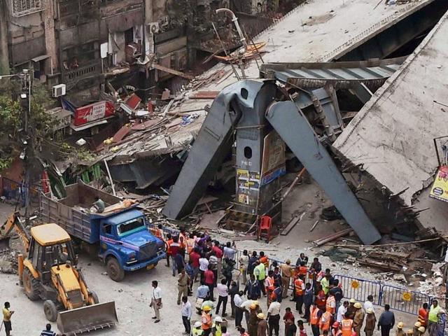 Curious onlookers peered over barriers at the accident site to get a glimpse of the mangled mess of metal and rubble, as police officers tried to push them back.(PTI Photo)