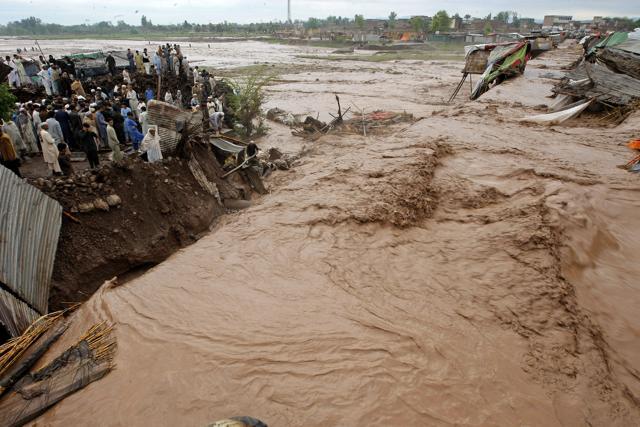 Pakistani villagers watch flash flooding on the outskirts of Peshawar on Sunday. (AP) Pakistani villagers watch flash flooding on the outskirts of Peshawar on Sunday. (AP)
