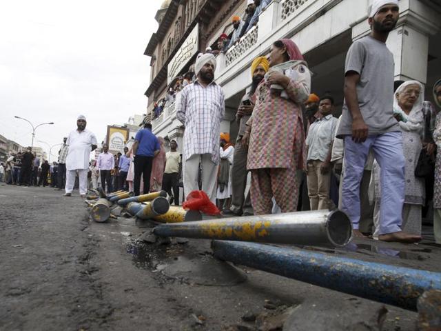 People wait outside Gurudwara Sis Ganj Sahib as the anti-encroahment drive begins.  (Sanchit Khanna/HT Photo) 