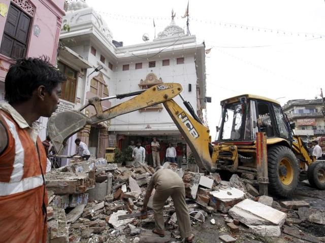 An MCD worker removes the rubble as a crane breaks demolish an illegally-constructed wall at Chandani Chowk. (Sanchit Khanna/HT Photo) 