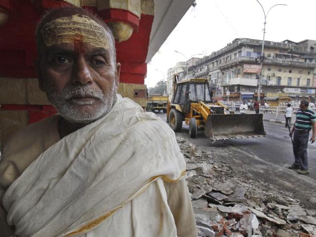 A priest stands next to a demolished religious structure.  (Sanchit Khanna/HT Photo) 