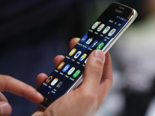 A sales assistant uses her mobile phone next to the company logos of Apple and Samsung at a store. The war between the rival smartphone makers is hotting up in the world’s fastest growing market. (HT Archive) A sales assistant uses her mobile phone next to the company logos of Apple and Samsung at a store. The war between the rival smartphone makers is hotting up in the world’s fastest growing market. (HT Archive)