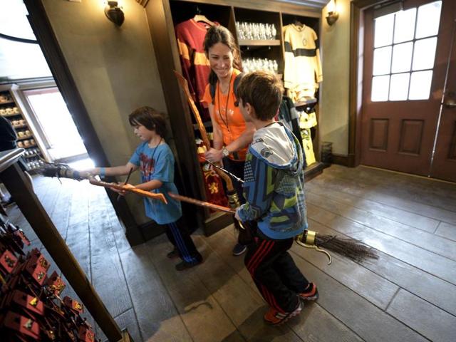 A mother and her children, try out brooms for sale inside Dervish and Banges general store in Hogsmeade Village during a soft opening and media tour of The Wizarding World of Harry Potter. (REUTERS)