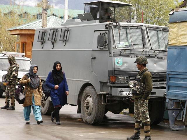 Students walk past the vehicles of Central Reserve Police Force (CRPF) at the National Institute of Technology (NIT) in Srinagar.(Waseem Andrabi / HT Photo)