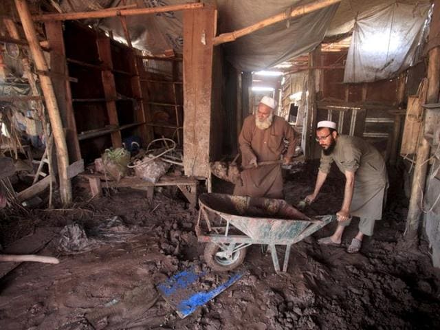Shopkeepers remove mud from their shop after floodwaters receded in Sarband area on the outskirts of Peshawar, Pakistan April 5, 2016. (REUTERS)