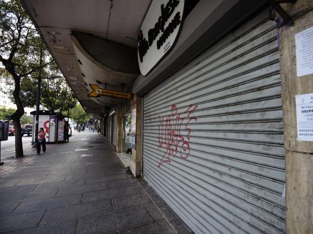 People walk past closed shops in a street of Caracas. Venezuelan workers will get Fridays off for the next two months as part of an emergency plan to save electricity.(AFP Photo)